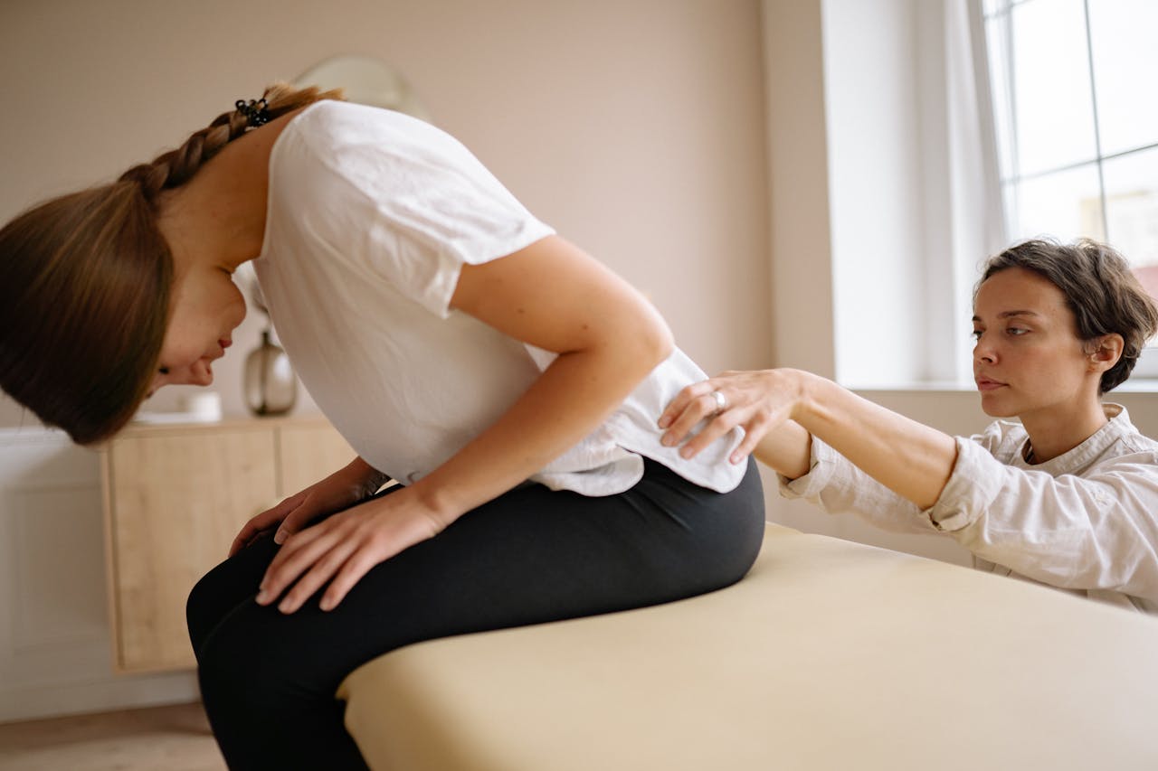 A therapist stretches a patients back during a physical therapy session indoors.